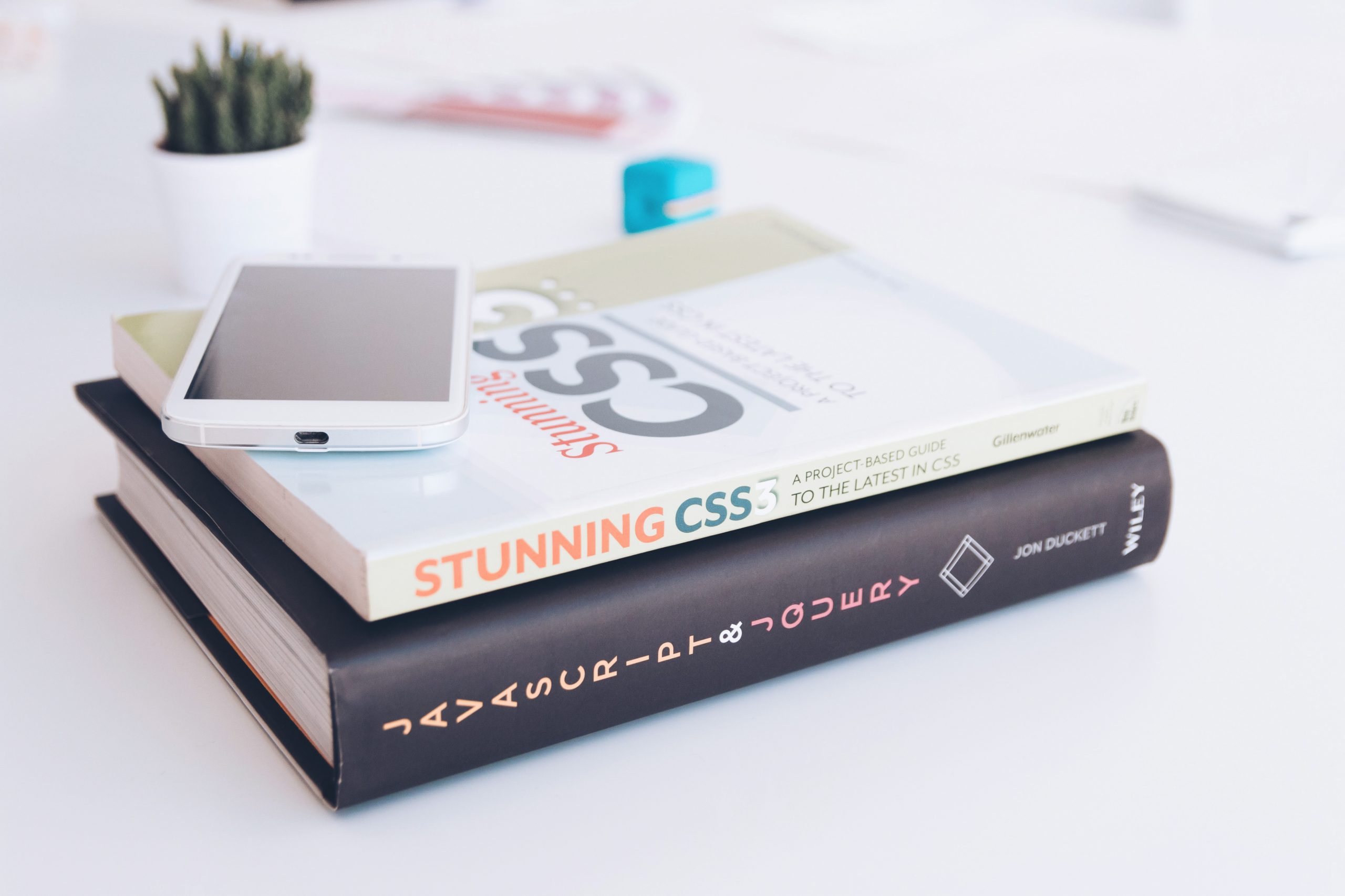 A book titled 'Stunning CSS' sits on top of another entitled 'JavaScript & JQuery".